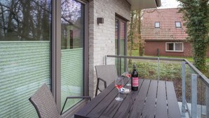 Un balcone con tavolo, due sedie e una bottiglia di vino.