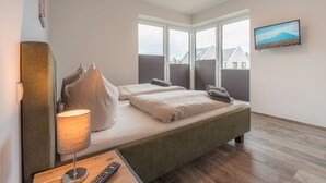 Camera d'albergo con un letto, una lampada, una TV e una finestra vista case.