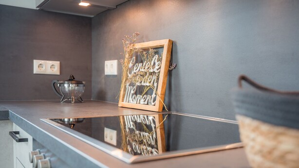Una cucina moderna con un piano di lavoro in acciaio inossidabile, un bollitore e una targa incorniciata al muro.