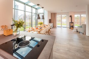 A modern kitchen with a large island, a dining area with a long table, and a fireplace.