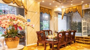 A hotel lobby with ornate wooden furniture, a large potted plant with pink flowers, and a marble floor. - Truc Huyen Hotel (Ho Chi Minh City)