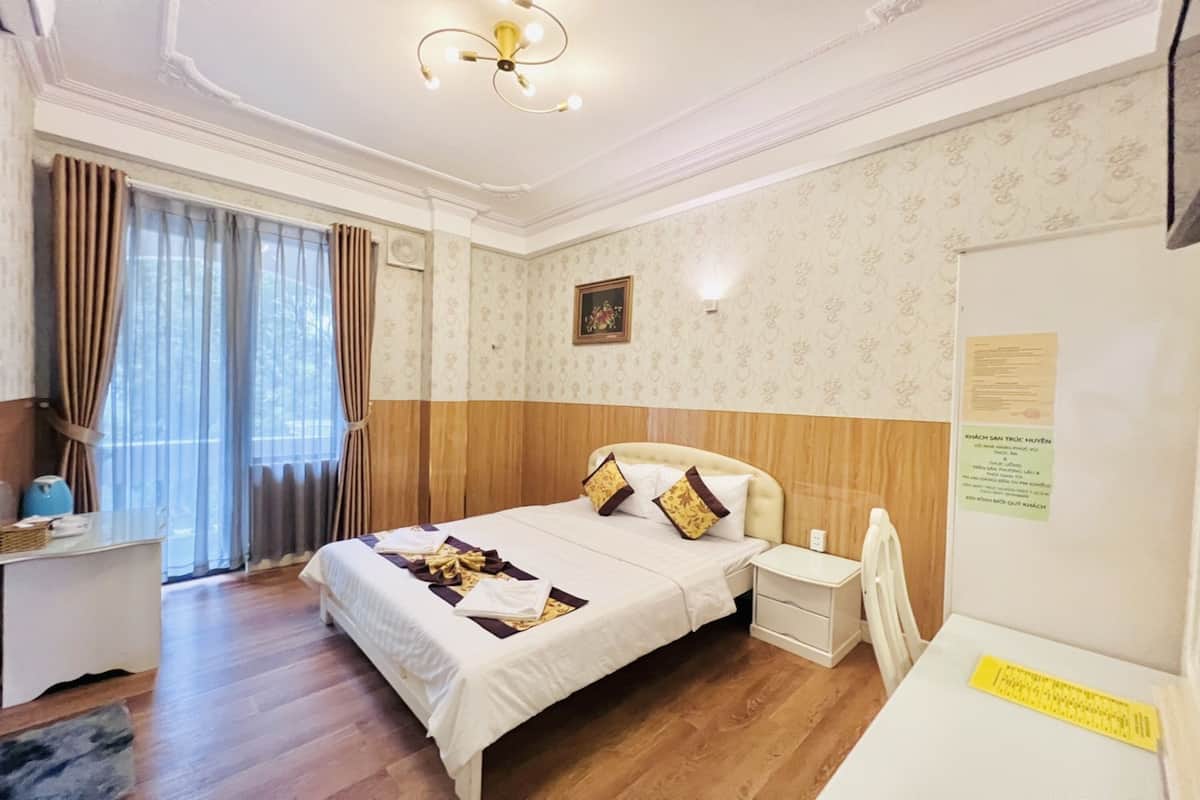 Ein Hotelzimmer mit Bett, Nachttisch, Schreibtisch und Vorhängen.