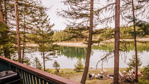 Eine Terrasse mit Blick auf einen See, mit Stühlen und einem Grill.