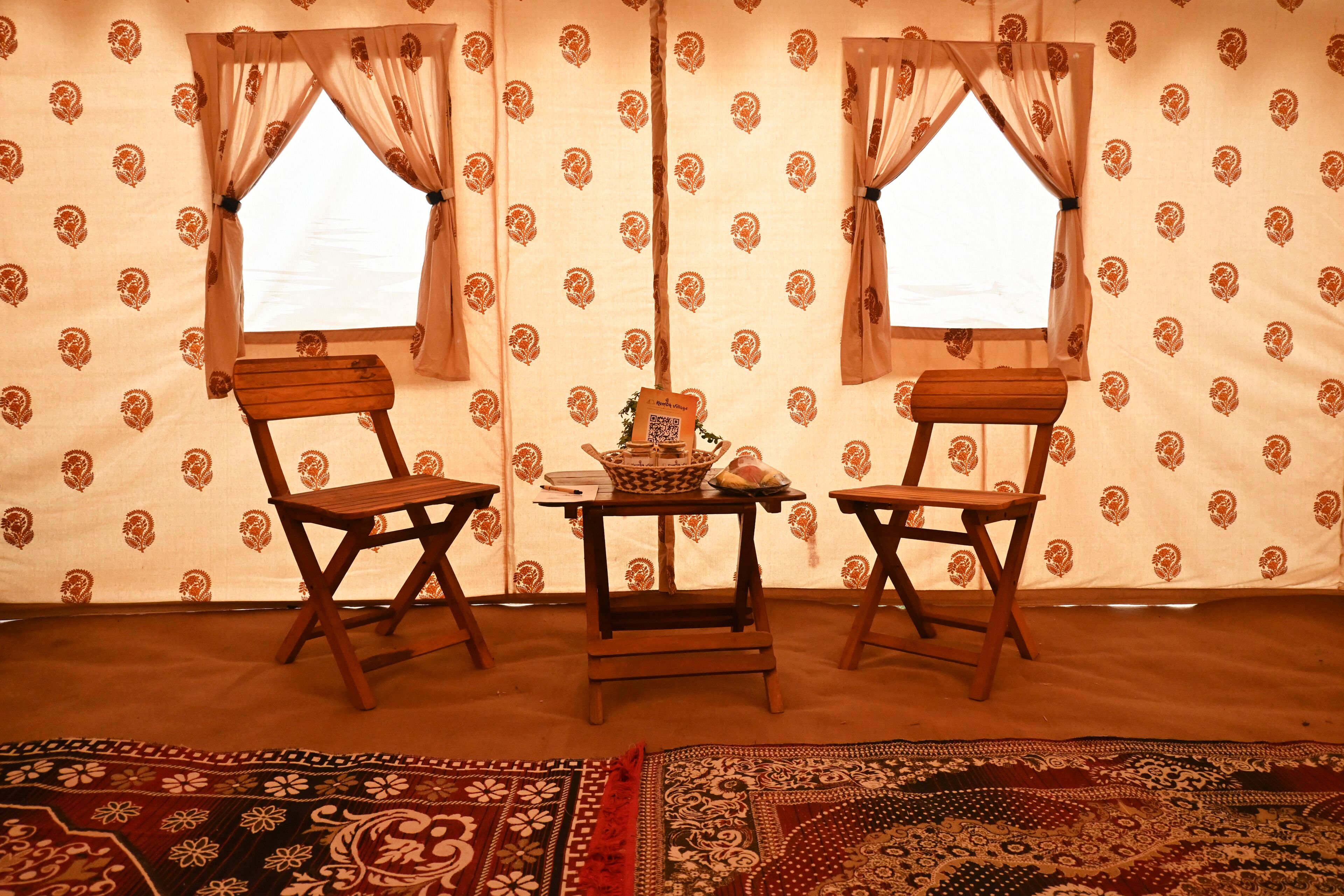 A room with two wooden chairs, a small table, and a patterned carpet.
