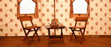 A room with two wooden chairs, a small table, and a patterned carpet.