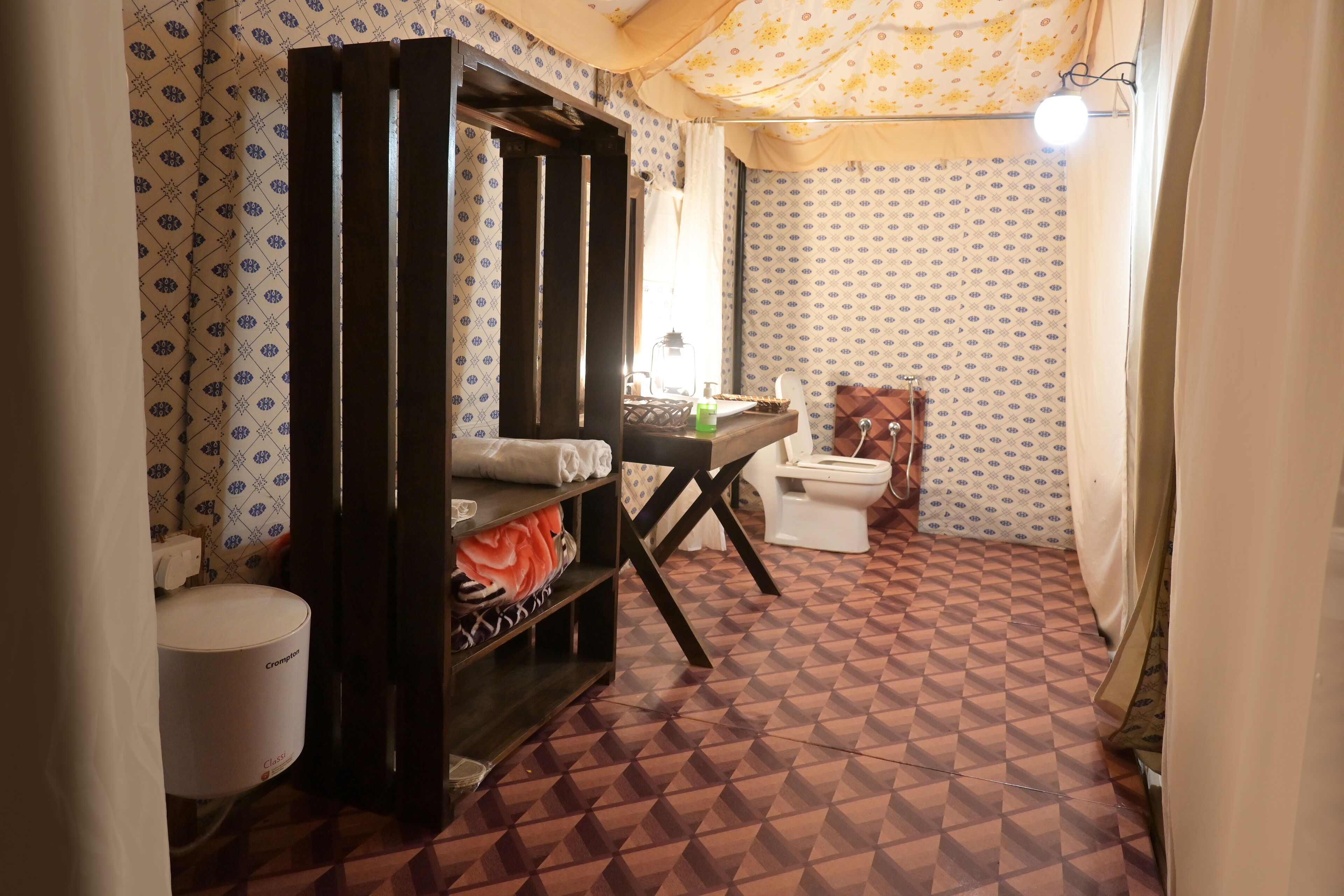 A compact bathroom with a patterned floor, a toilet, a sink, and a shelf with toiletries.