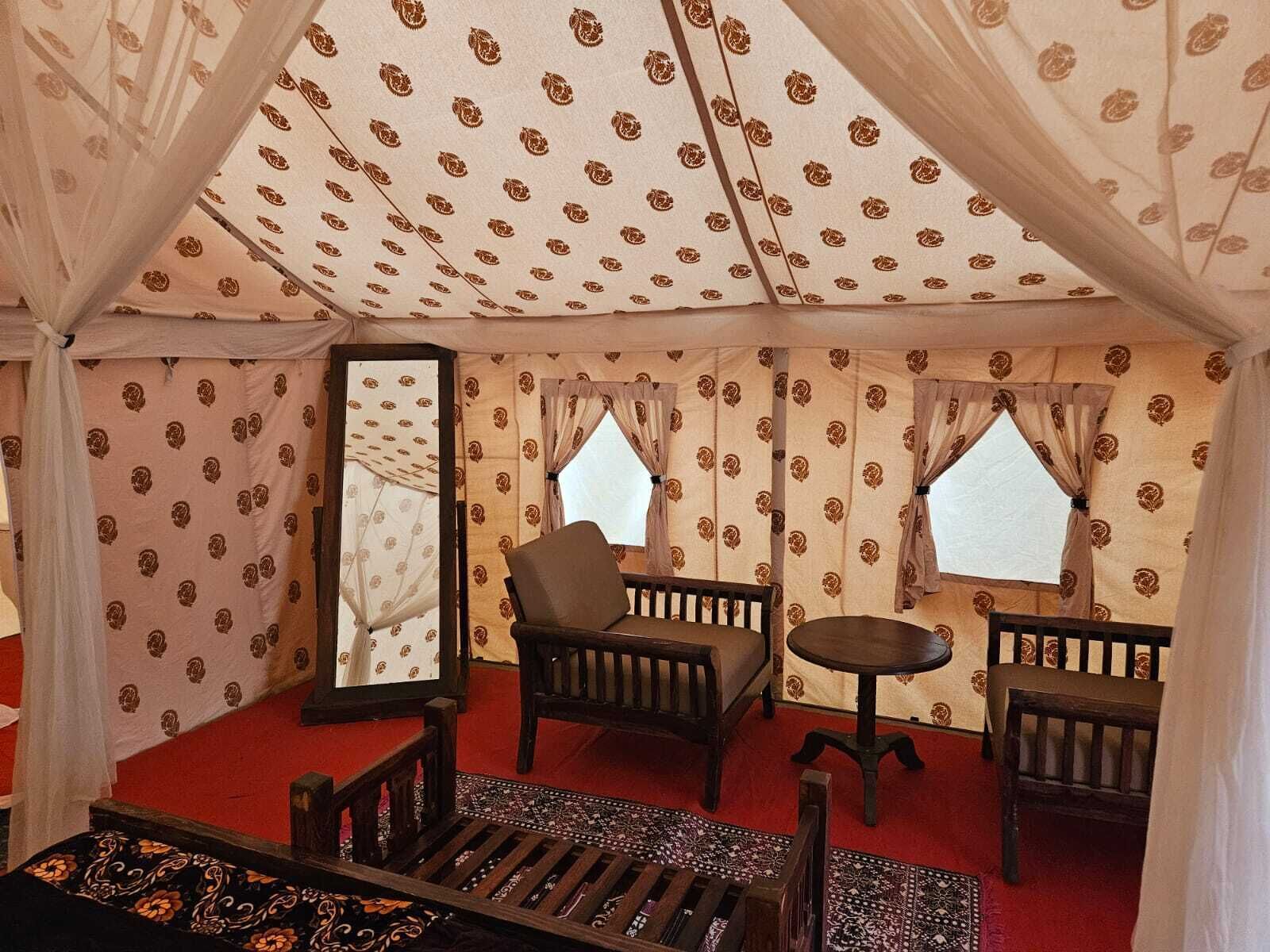 A tent with patterned walls, two windows, and a central seating area with a table and chairs.