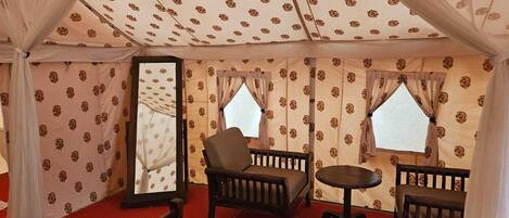 A tent with patterned walls, two windows, and a central seating area with a table and chairs.