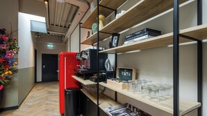 A modern interior with wooden shelves, a red refrigerator, and a coffee machine. - Badhuis Hotel (Utrecht)