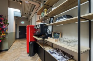 A modern interior with wooden shelves, a red refrigerator, and a coffee machine.