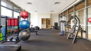 Una palestra con attrezzi per l'allenamento, un tapis roulant e una parete con finestre.