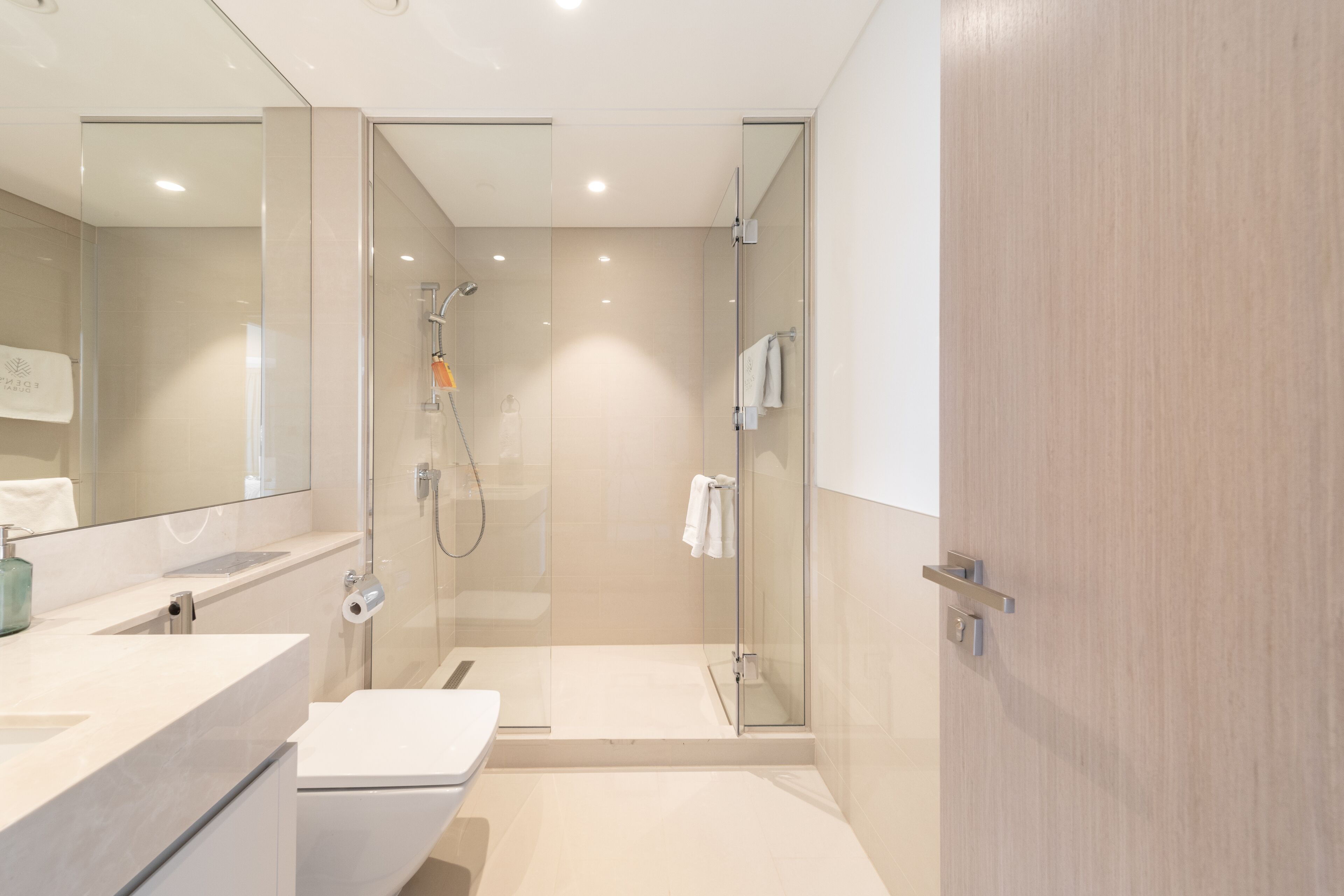 A modern bathroom with a glass-enclosed shower, a white sink, and a toilet.