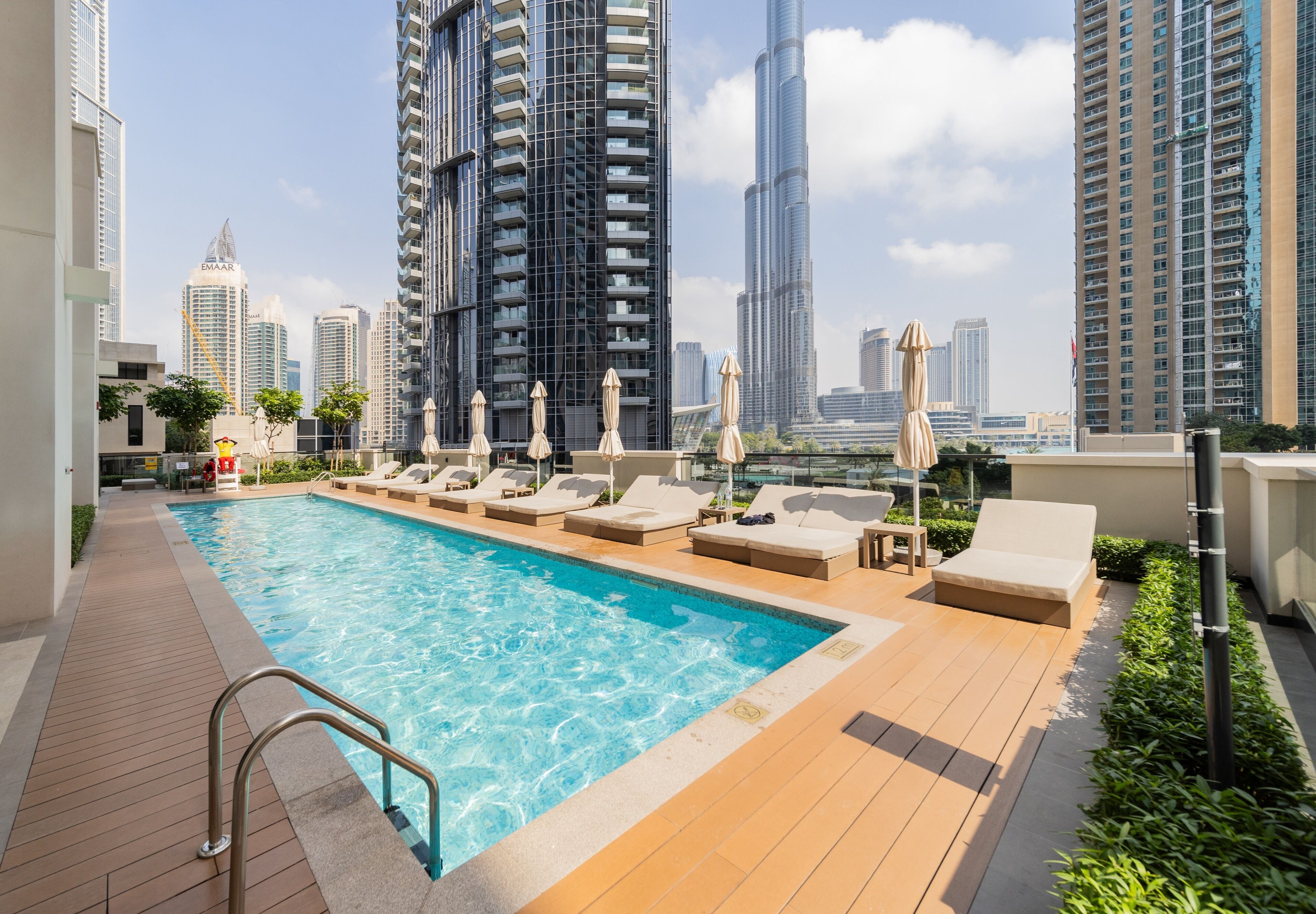 Een buitenzwembad, parasols bij het zwembad en ligstoelen