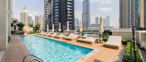 Een buitenzwembad, parasols bij het zwembad en ligstoelen