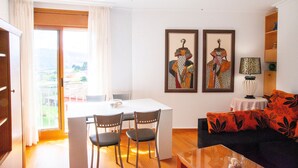 Un coin repas avec une table et des chaises, un canapé agrémenté de coussins à motifs et deux œuvres d’art encadrées accrochées au mur.