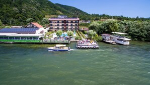 Ein Hotel am Flussufer mit Anlegesteg, Boot und einem Gebäude mit Solaranlage.