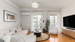 Una sala de estar moderna con un sofá, una mesa de centro, un televisor y un ventanal con vistas a edificios.