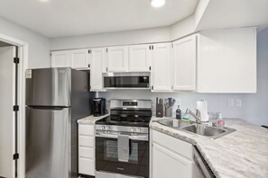 A modern kitchen with white cabinets, stainless steel appliances, a built-in oven, and a microwave. - Dreamy Dells Oasis for Families & Couples (Wisconsin Dells)