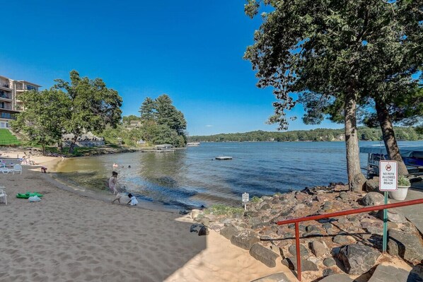 Une plage où les animaux de compagnie ne sont pas autorisés, une rive sablonneuse et un lac paisible en arrière-plan.
