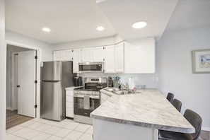 A modern kitchen with white cabinets, stainless steel appliances, and a marble countertop. - Dreamy Dells Oasis for Families & Couples (Wisconsin Dells)