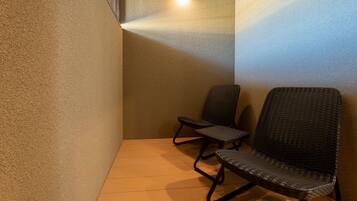 A corner of a room with two wicker chairs and a wooden floor.