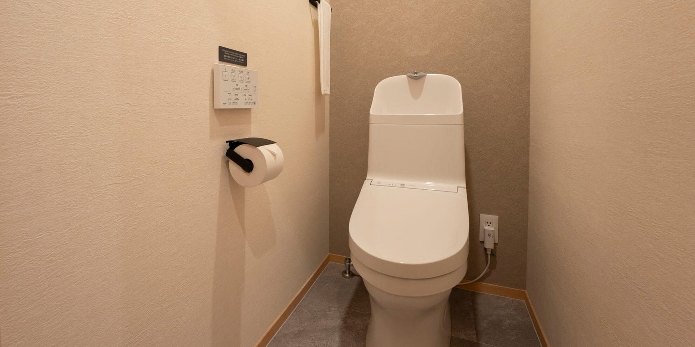 A small bathroom with a toilet, a paper towel dispenser, and a wall-mounted calendar.