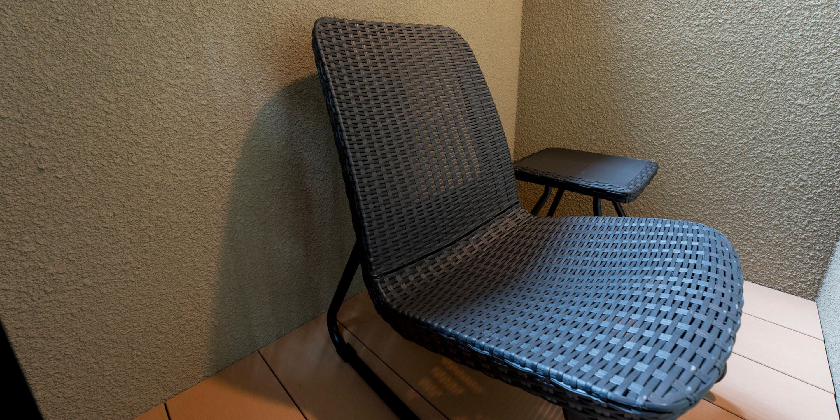 Un coin de pièce avec un fauteuil en osier et une petite table.