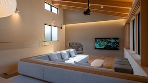 Un saló modern amb un sofà modular, una televisió de pantalla plana i un sostre de fusta.