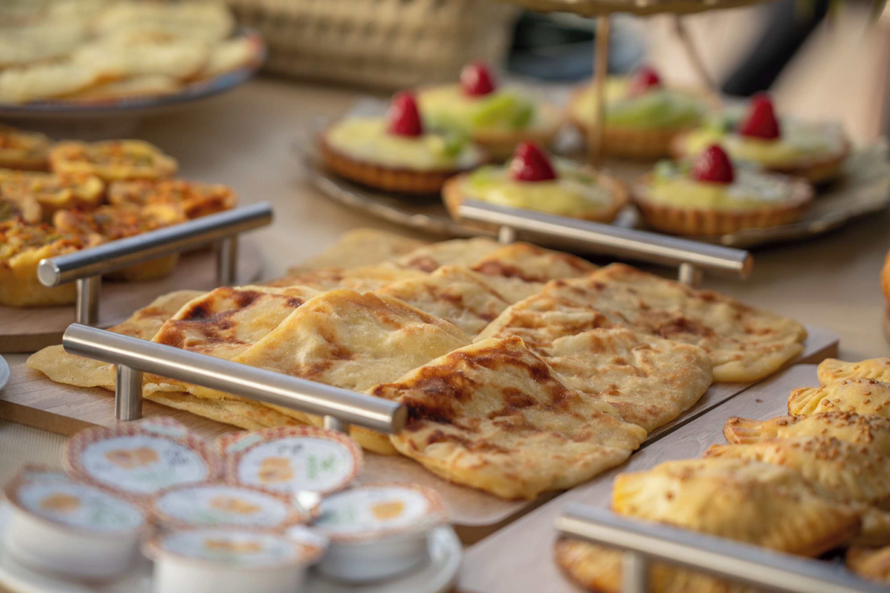 A buffet with various food items including flatbreads, pastries, and desserts.