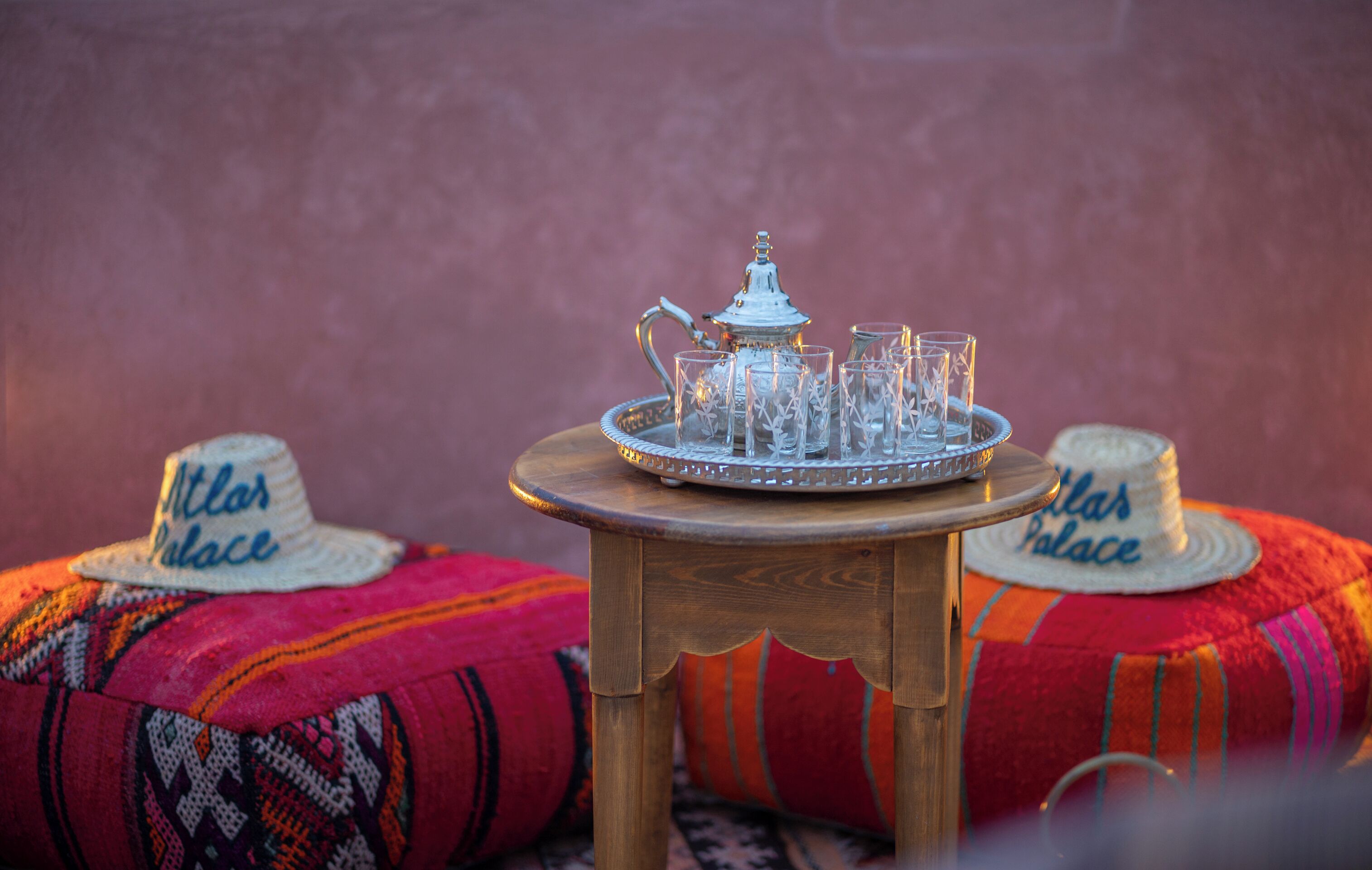 A table with a teapot and glasses, surrounded by colorful pillows and a sign reading "Atlar Palace".