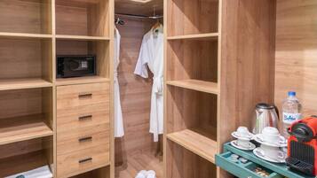 A compact hotel room with wooden shelving, a microwave, a small refrigerator, and a coffee maker.