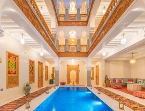 A luxurious indoor swimming pool with ornate architecture, a grand staircase, and a cozy seating area. - Riad Atlas Palace (Marrakech)
