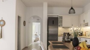 Een moderne keuken met witte kasten, een roestvrijstalen koelkast en een eethoek met een houten tafel en witte stoelen.