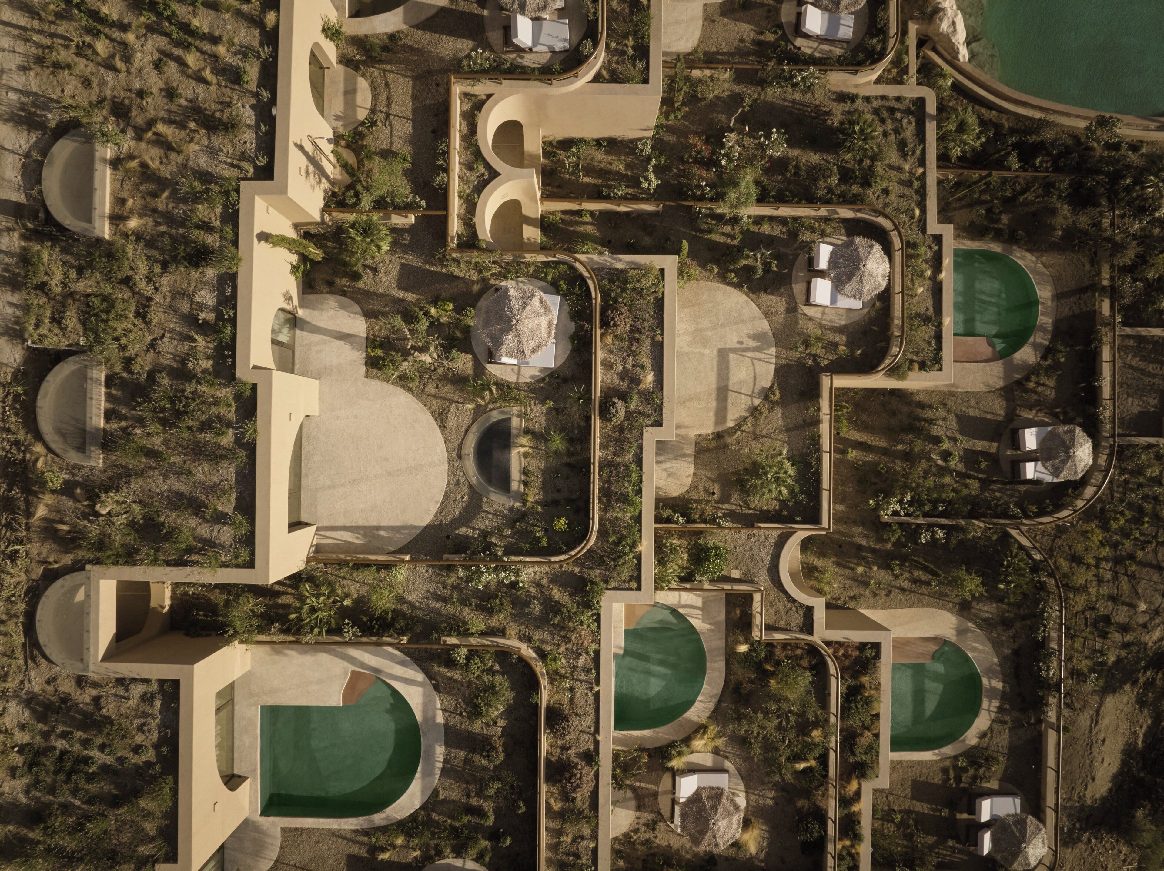 Vista aérea de un complejo turístico con varias piscinas, jardines ajardinados y senderos.