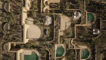 Vista aérea de un complejo turístico con varias piscinas, jardines ajardinados y senderos.