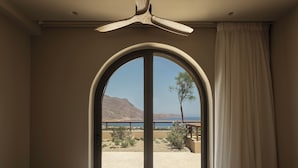Ein Hotelzimmer mit einem großen Bogenfenster, einem Bett und einem Deckenventilator.