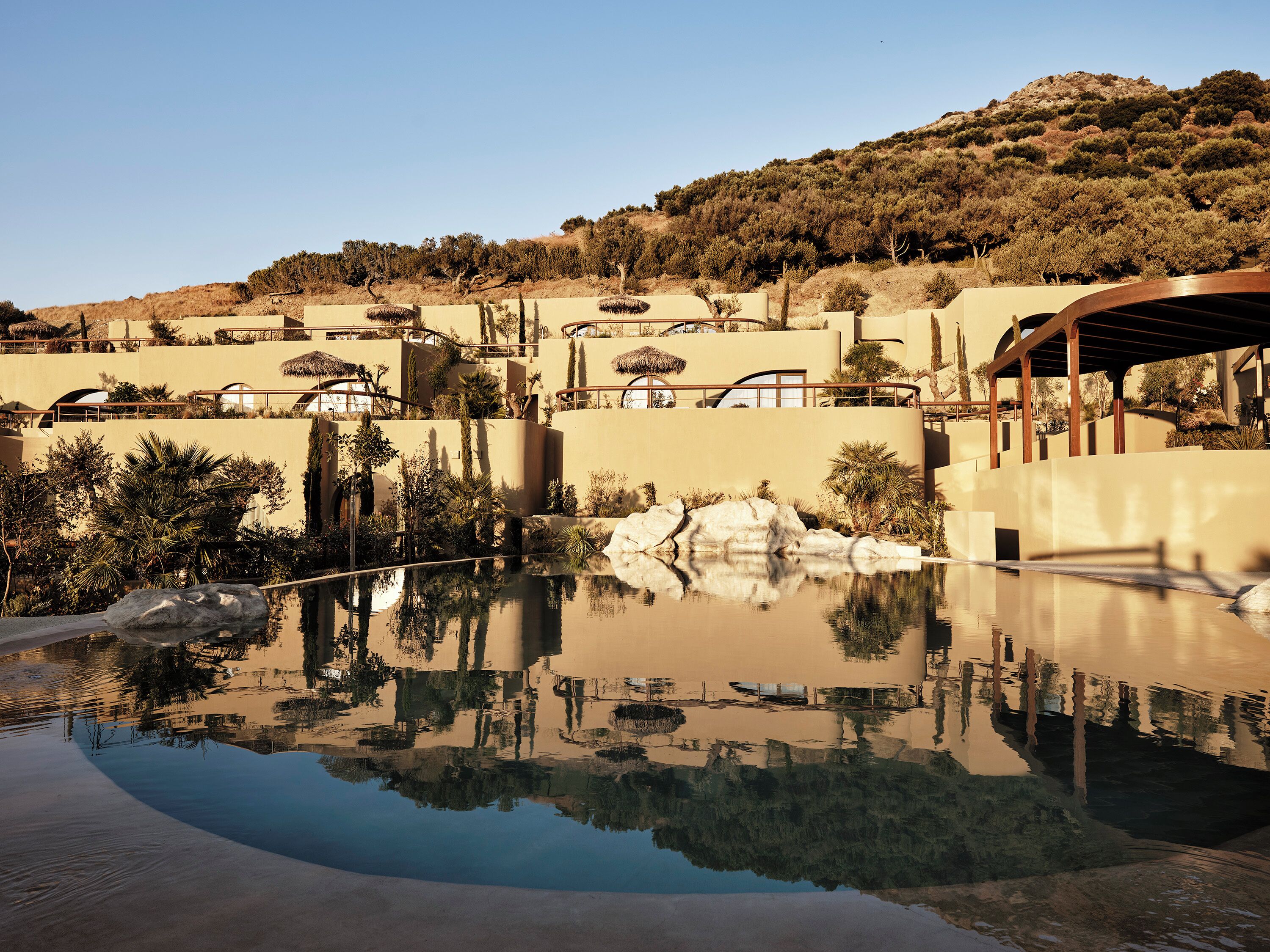 Un complexe hôtelier doté d’une piscine qui reflète l’architecture environnante et le paysage naturel.