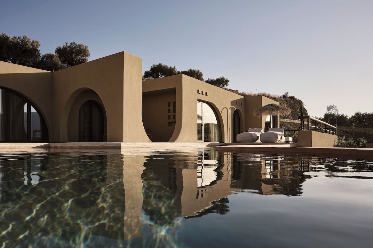 Un bâtiment moderne doté de fenêtres en arc de cercle et d’une piscine qui reflète son architecture.