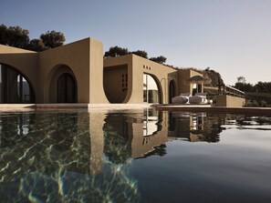 A modern building with arched windows and a pool reflecting its structure. - Tella Thera, a Member of Design Hotels (Kissamos)