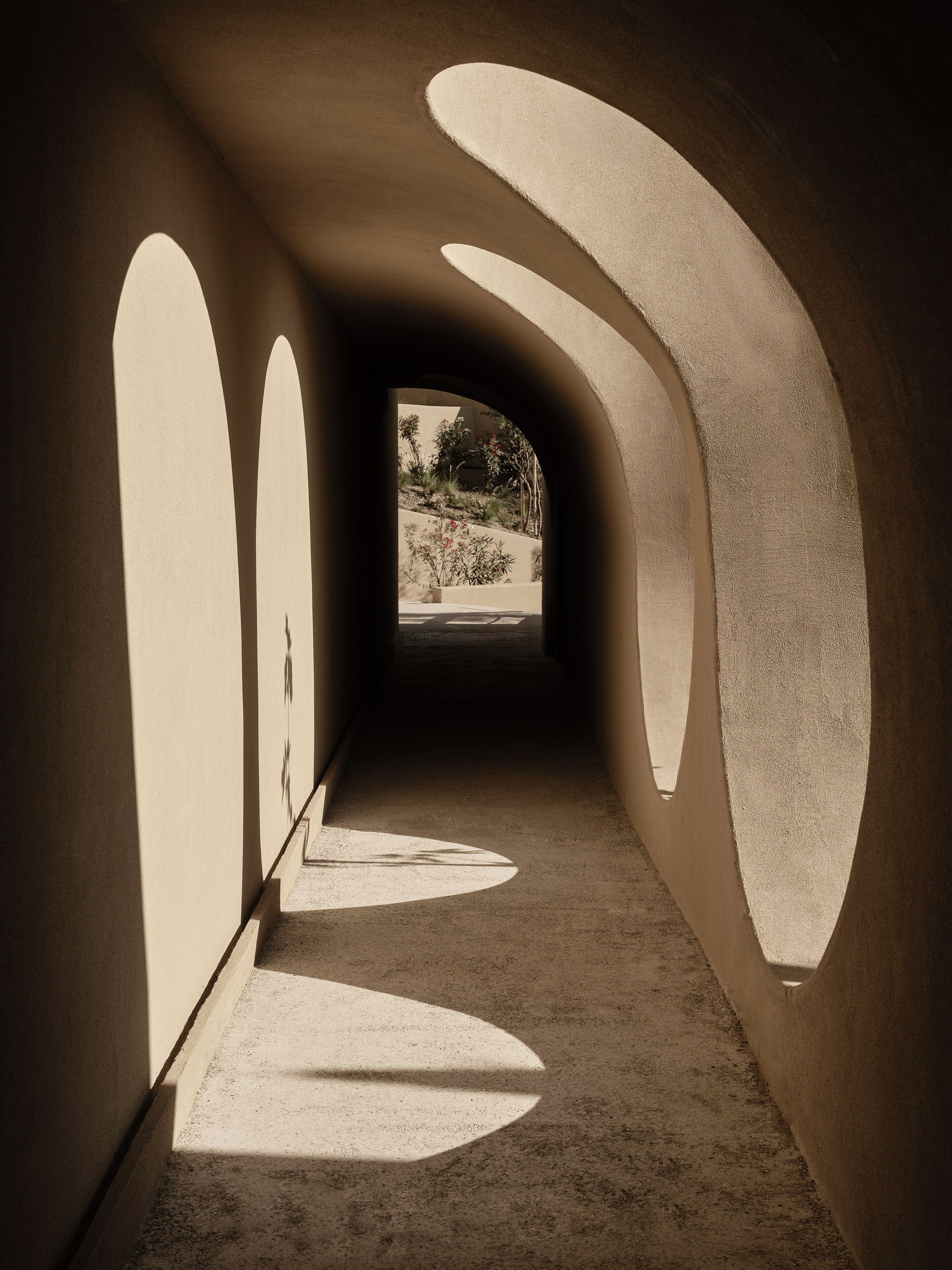 A corridor with arched ceilings and shadows cast on the floor.