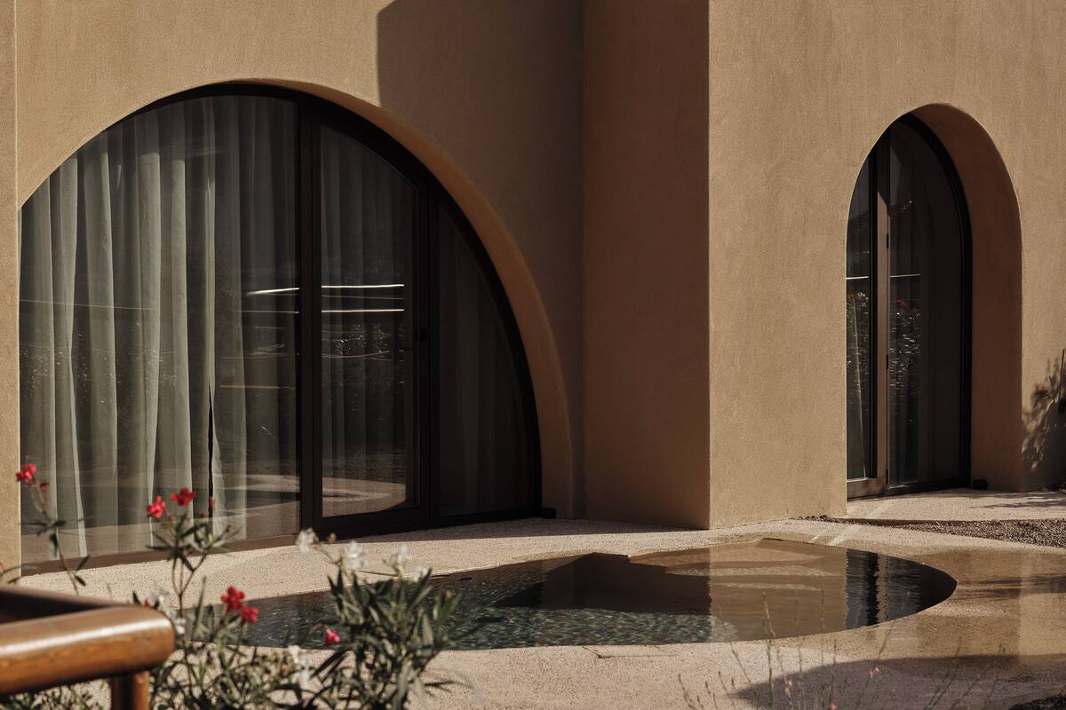 Un bâtiment moderne doté de grandes fenêtres en arc de cercle et d’une petite fontaine dans la cour.