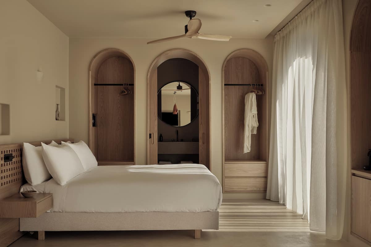 Une chambre à coucher moderne avec un grand lit, un dressing et un ventilateur de plafond.