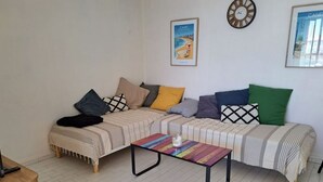 Uma sala de estar com sofá, mesa de centro e relógio na parede.