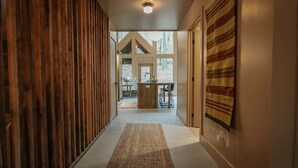 Un couloir avec un mur recouvert de lambris en bois, un tapis tissé et un tapis à rayures sur le côté droit.