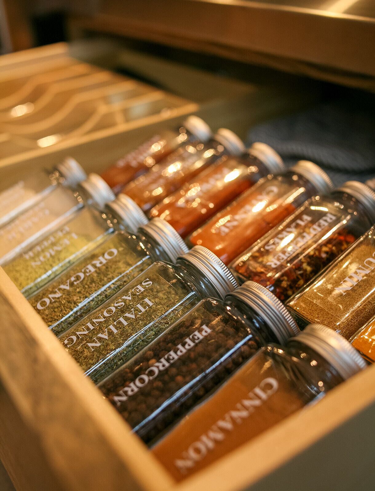 A drawer with multiple spice jars labeled with various names.