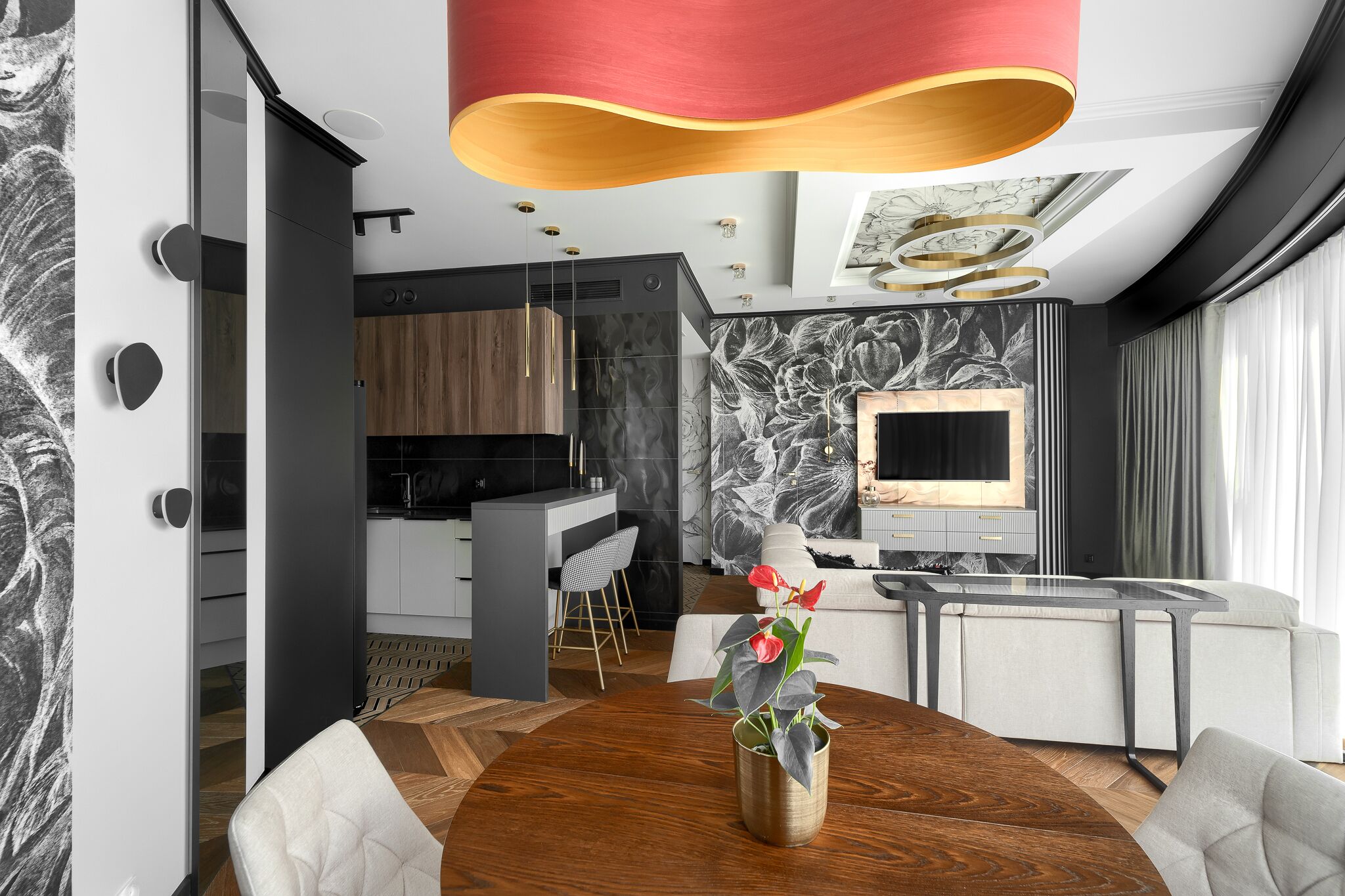 Una cocina moderna con una isla central, un comedor con mesa y sillas de madera, y una sala de estar con sofá y televisor.