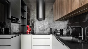 Een moderne keuken met een zwarte afzuigkap, een koffieapparaat en een roestvrijstalen spoelbak.