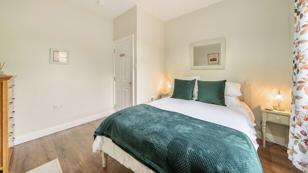 A bedroom with a bed, bedside tables, a mirror, and a door.