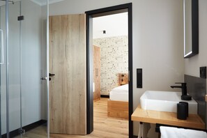 Ein modernes Badezimmer mit Holztür, Waschbecken und Spiegel.
