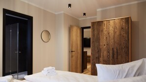 Ein modernes Hotelzimmer mit einem Bett, einem Holzschrank, einem runden Spiegel und einer Tür zu einem Badezimmer.